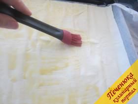 4) Покласть 1 лист слоёного теста на пекарскую бумагу. Кулинарной кисточкой обмазать тесто желтком.