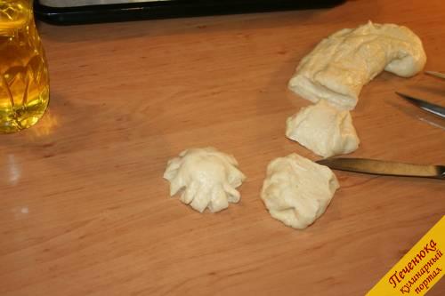 8) Смазываем руки и стол растительным маслом. Выкладываем тесто на стол. Начинаем его разделывать. Нарезаем тесто небольшими брусочками. Скатываем шарики и, немного приплюснув их посередине, надрезаем края. Таким образом, формируем сдобные дрожжевые булочки.
