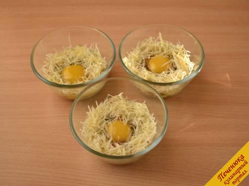 7) Аккуратно разбить в каждую чашечку яйцо, стараясь не повредить желток. Вокруг желтка посыпать твердым сыром, натертым на мелкой терке.